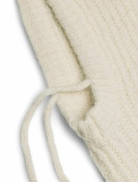 Primo piano di un maglione cream lavorato a maglia, con un design testurizzato a coste e dettagli con cordino al collo, realizzato in un morbido e soffice filato.