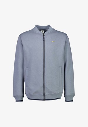 lichtblauwe ritsjack met een ribbelkraag en manchetten, voorzien van twee zijzakken en een kleine gouden accent op de borst. Zachte textuur.