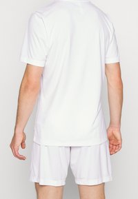 Camiseta y pantalones cortos deportivos blancos, de mangas cortas, textura suave, material ligero, diseño minimalista, adecuados para deportes o vestimenta casual.