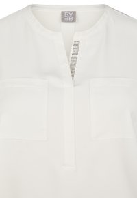 Weiße Bluse mit V-Ausschnitt, ausgestattet mit einer dekorativen Reihe von Nieten an der Knopfleiste und zwei Brusttaschen, gefertigt aus einem glatten Stoff.