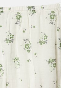 Tecido com padrão floral sobre um fundo creme claro. Apresenta pequenas flores verdes e cinzas, textura ligeiramente amassada e cintura elástica.