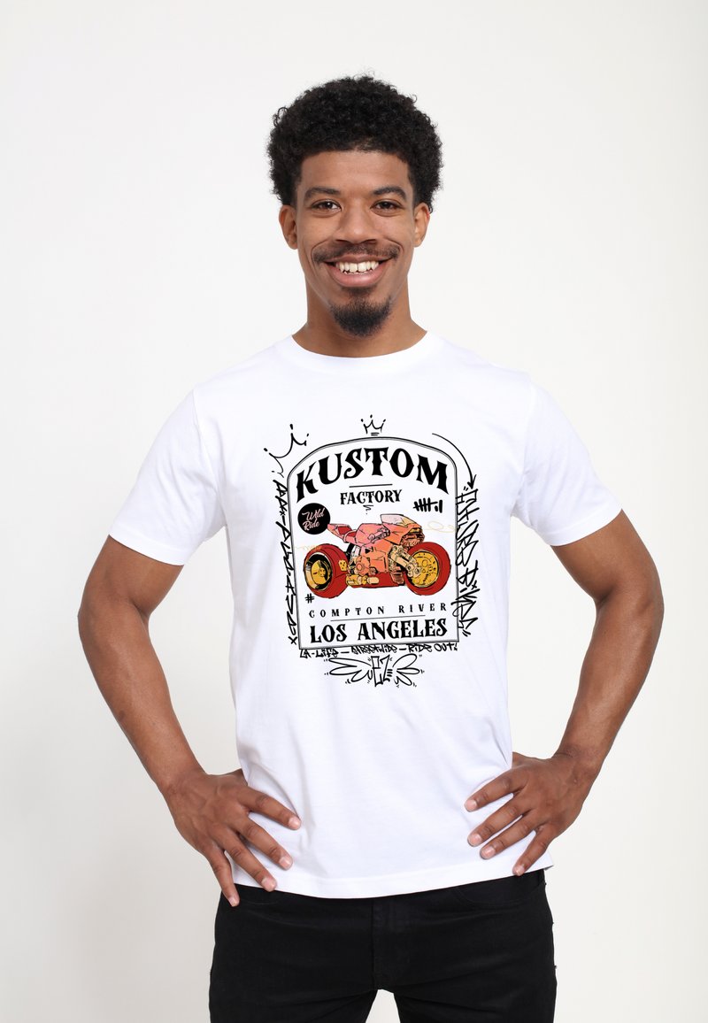 Bílý tričko s grafickým designem obsahujícím text "KUSTOM", barevnou ilustraci motocyklu a černý obrys, umístěné na jednoduchém pozadí.