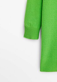 Pull vert tricoté avec une finition texturée, des poignets côtelés et une coupe droite. Le matériau semble doux et léger.