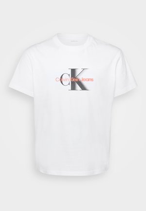 White cotton t-shirt featuring a large black "K" logo with "Calvin Klein Jeans" in pink text below. Round neckline and short sleeves.