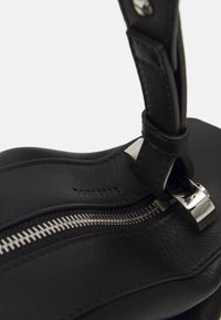 Borsa a tracolla in pelle nera con una texture liscia, dotata di una cerniera argentata e minuteria metallica. Include un dettaglio decorativo sulla tracolla.