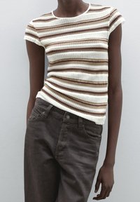 Striped knit top in cream, brown, and tan colors, featuring short sleeves, a round neckline, and textured ribbing details. Paired with dark brown pants.