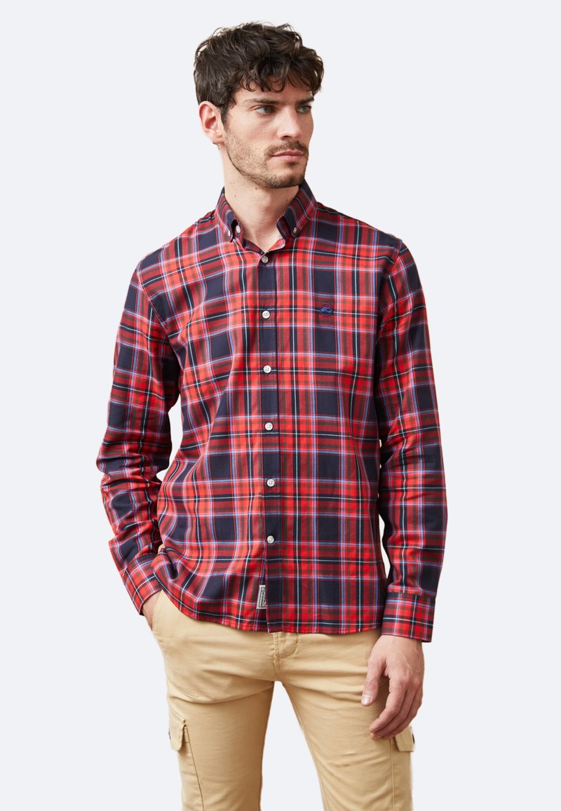 Camisa de cuadros roja y azul marino con cuello abotonado, mangas largas y un bolsillo en el pecho. Tejido de algodón con una textura suave.