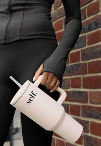 Roze geïsoleerde drinkbeker met een handvat en rietje, voorzien van een zwarte rand en het woord "self." gedrukt in zwarte letters. Soepele matte afwerking.