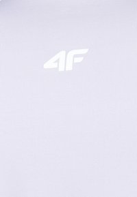 Jasnofioletowa koszulka sportowa z gładkiego materiału, z teksturowaną powierzchnią i białym logo "4F" z przodu.