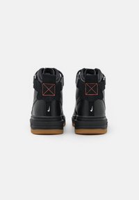 Svarta hög-top sneakers i läder, med orange sömmar, en texturerad yta och en sula av gummi med vit logotyp accent.