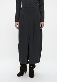 Schwarze, weit geschnittene Hose mit hoher Taille, ausgestattet mit Falten und Seitenknöpfen. Hergestellt aus glattem Stoff, gestaltet für eine fließende Silhouette.