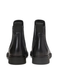 Sorte lær ankelsko med elastiske sidepaneler, glatt tekstur og flate gummisåler; minimalistisk design som viser rene linjer.