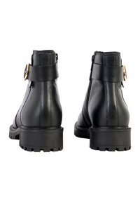 Botas de tobillo de cuero negro con punta redonda, suela de goma gruesa y cierre de cremallera en el costado. Presentan una amplia correa y un acento de hebilla de metal.