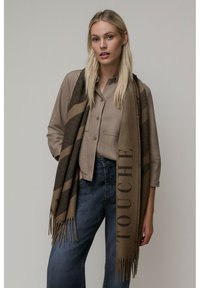 Écharpe en laine marron avec des bords à franges, présentant un motif rayé et le mot « TOUCHE » imprimé en évidence sur un côté.