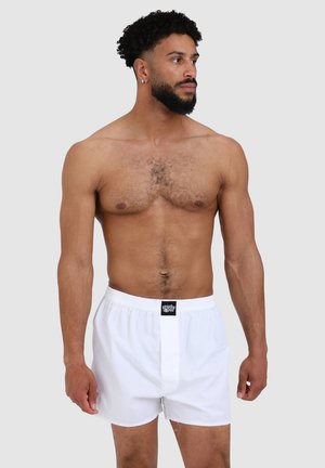 Weiße Baumwollboxershorts mit elastischem Bund und einem kleinen schwarzen Logostreifen vorne. Glatte Textur, standardmäßige lockere Passform.