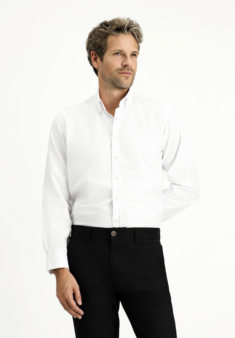 Biała koszula z długim rękawem, z kołnierzykiem, w połączeniu z czarnymi spodniami; gładki materiał; klasyczny krój z zapięciem na guziki z przodu i przy mankietach.