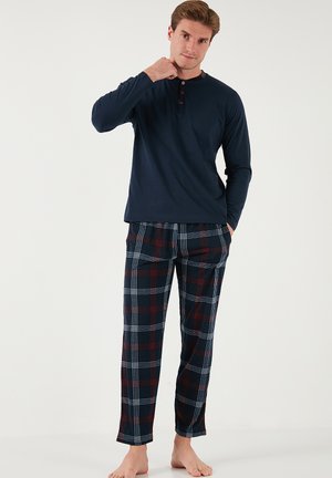 Haut à manches longues bleu marine avec un col boutonné, associé à un pantalon à carreaux bleu marine, rouge et blanc. Tissu doux et coupe ample pour le confort.