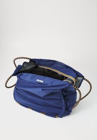 Sac en tissu bleu marine avec surface texturée, grande ouverture et poignées tressées avec des accents jaunes. Intérieur doublé en gris.