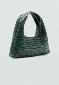 Bolso de mano tejido en verde oscuro con un asa curvada, forma triangular y patrón texturizado, que presenta un interior liso y sin herrajes visibles.