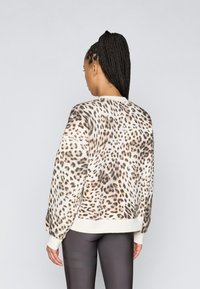 Φούτερ με λεοπάρ σχέδιο και μακριά μανίκια, με κρέμα χρώματος μανίκια και στρίφωμα. Μαλακό ύφασμα με χαλαρή εφαρμογή, σχεδιασμένο για καθημερινή χρήση.