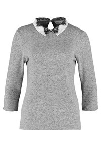 Grå långärmad topp med rundad nederkant, som har en vit krage prydd med svart spetsdetalj. Mjuk tyg med texturerad finish.