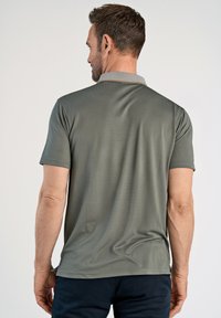 Lyhythemmattu polo-paita hillityssä vihreässä kankaassa, jossa on kaulus vaaleanharmaalla reunuksella, sileä rakenne ja rento istuvuus.