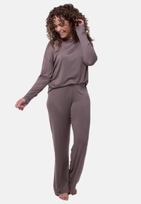 Lös passform, långärmad jumpsuit i mjukt, stretchigt taupe-tyg. Har en avslappnad halsringning och vida ben, vilket ger komfort och lätthet.