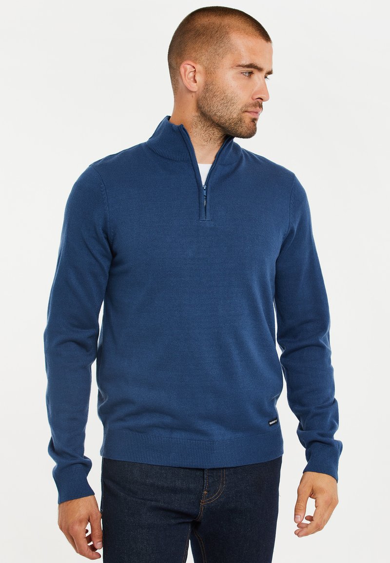 Blauer Strickpullover mit hohem Kragen und Viertel-Reißverschluss. Verfügt über gerippte Bündchen und Saum, aus einem weichen, strukturierten Stoff gefertigt.