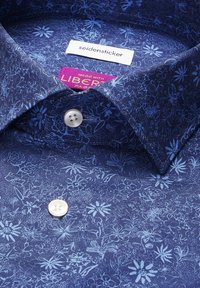 Chemise bleue à motif floral avec boutons blancs et étiquettes portant les mentions "seidensticker" et "Liberty Fabric."
