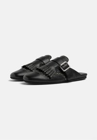 Crne kožne cipele na slip-on s značajkom remena s kopčom, detaljima od resica i zakovicama duž ruba. Glatka tekstura, minimalistički dizajn.
