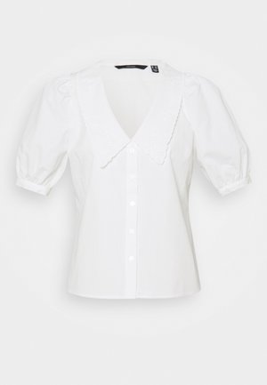 Blusa blanca de manga corta con gran cuello festoneado, pequeños detalles de ojales, mangas abullonadas y cierre frontal con botones.