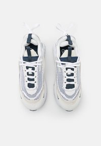 Chaussures de sport blanches en mesh et suède, avec des accents bleu marine, bout rond, semelle épaisse et lacets plats.