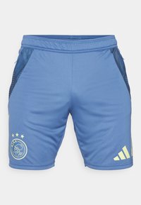 Siniset urheilushortsit, jotka on valmistettu hengittävästä kankaasta. Ne sisältävät tumman verkkokangaspaneelin sivuilla, kirjotun logon ja keltaisia yksityiskohtia.