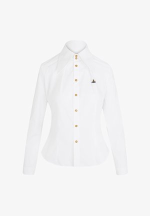 Chemise blanche à manches longues avec un large col, des boutons dorés, et un petit emblème coloré sur le côté gauche, fabriquée en tissu de coton lisse.