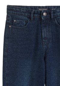 Jean en denim bleu foncé à coupe droite, avec une fermeture à bouton, cinq poches et des détails de couture subtils sur le tissu.
