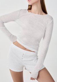 Biała, fakturowana bluzka z długim rękawem i szorty, z prążkowanym wzorem, okrągłym dekoltem oraz dekoracyjnymi guzikami na szortach.