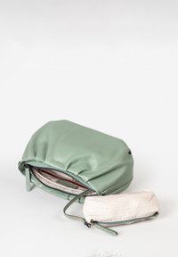 Grüne Leder-Schultertasche mit gerafftem oberen Teil, ausgestattet mit einem Reißverschluss und einem kleinen abnehmbaren Täschchen aus einem hellen, gemusterten Stoff.