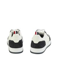 Sneakers z białą skórzaną cholewką z granatowymi akcentami ze zamszu, okrągłym noskiem, płaską gumową podeszwą oraz małą naszywką w czerwono-biało-niebieskie kolory.