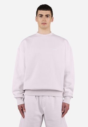 Light pink crewneck sweatshirt with ribbed cuffs, matching elastic waistband, and subtle branding on the chest. Soft fabric texture.