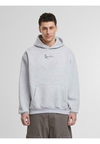 Sudadera de algodón gris con bolsillo canguro, puños y dobladillo acanalados, y un pequeño diseño de firma negra en el pecho.