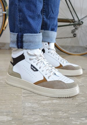 Zapatillas alta con cuero blanco y acentos de gamuza gris y marrón, detalles perforados y una suela de goma texturizada.