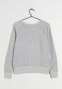 Sudadera gris con cuello redondo, mangas raglán y detalles de costuras en rosa. Confeccionada en un material suave, con puños y dobladillo acanalados.