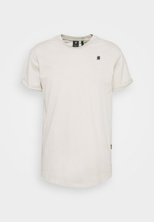 Short-sleeve, crew-neck t-shirt in beige cotton, featuring a small black logo on the chest and a side tag near the hem.