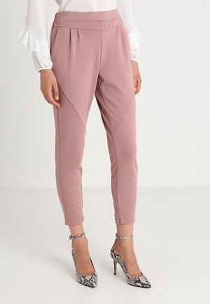 Pantalons tapered rose clair avec des plis, dotés d'une texture lisse et d'un design ajusté aux chevilles. Assortis à des escarpins à motif serpent.
