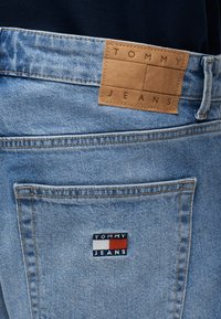 Πίσω τσέπη σε ανοιχτό μπλε τζιν με κεντημένο λογότυπο Tommy Jeans και δερμάτινη ετικέτα στη μέση.