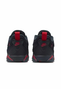 Baskets noires avec des accents rouges, présentant des surfaces texturées et un col rembourré. Le talon comprend une languette et un logo embossé.
