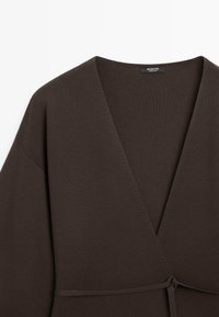 Donkerbruine gebreide wikkelcardigan met V-hals, lange mouwen en een dun ceintuurriempje in de taille, met het label Massimo Dutti.