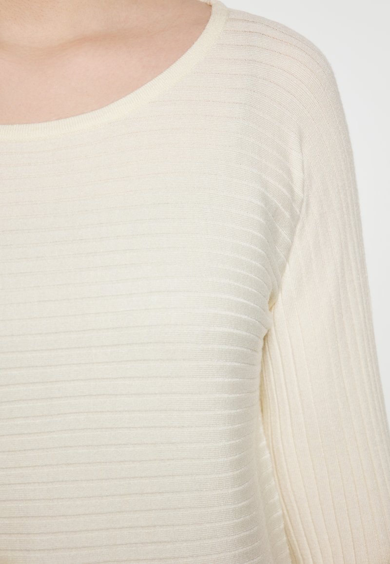 Maglione a coste di un beige chiaro con scollatura tonda, caratterizzato da un motivo testurizzato e maniche lunghe, realizzato in un tessuto morbido e leggero.