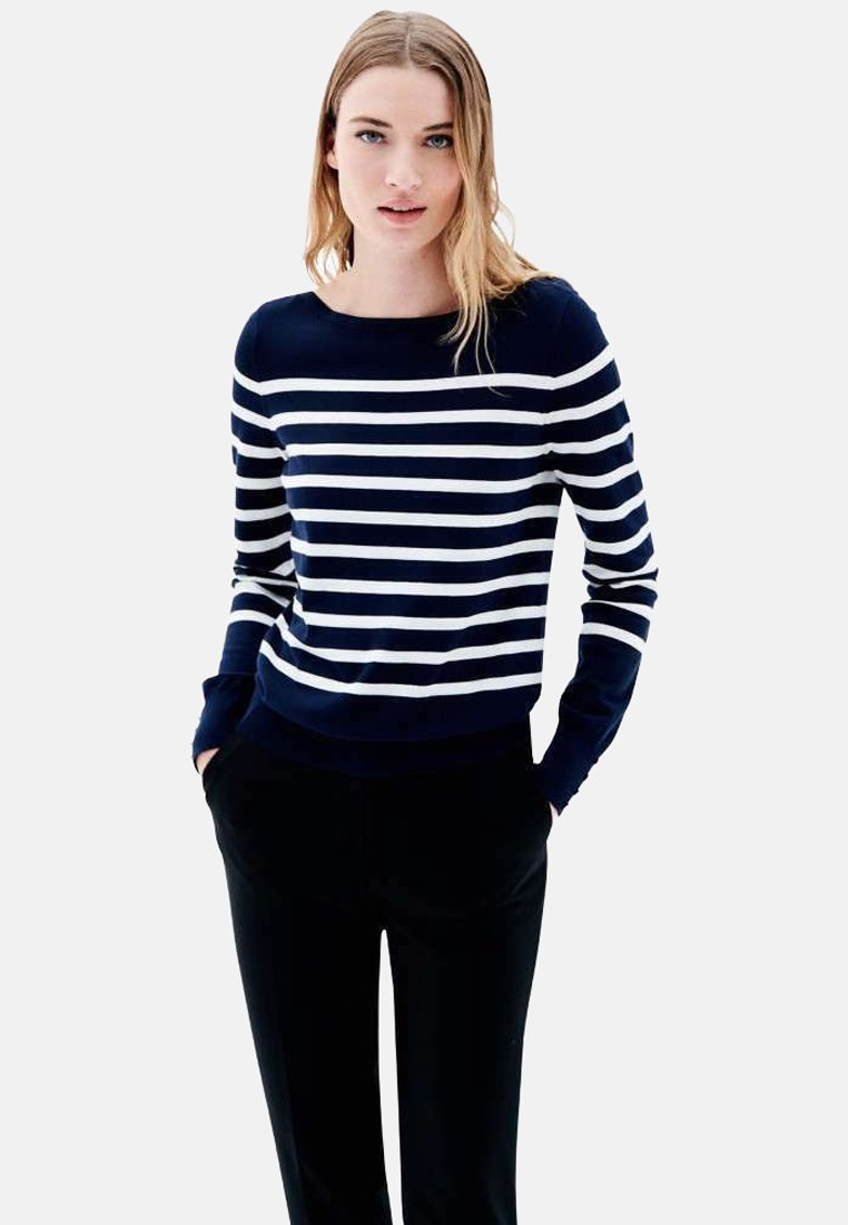 Pull long à rayures bleu marine et blanc, avec un col rond et des poignets côtelés, associé à un pantalon noir. Texture douce, coupe décontractée.