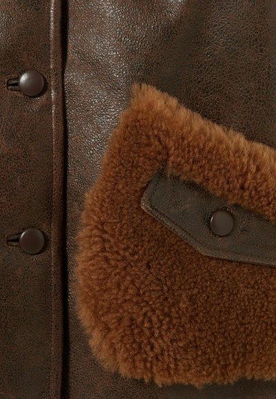 Veste en cuir marron avec une finition texturée, détail de poche en fausse fourrure marron et boutons ronds foncés.